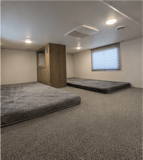 Carpeted bunk room with two mattresses and a window