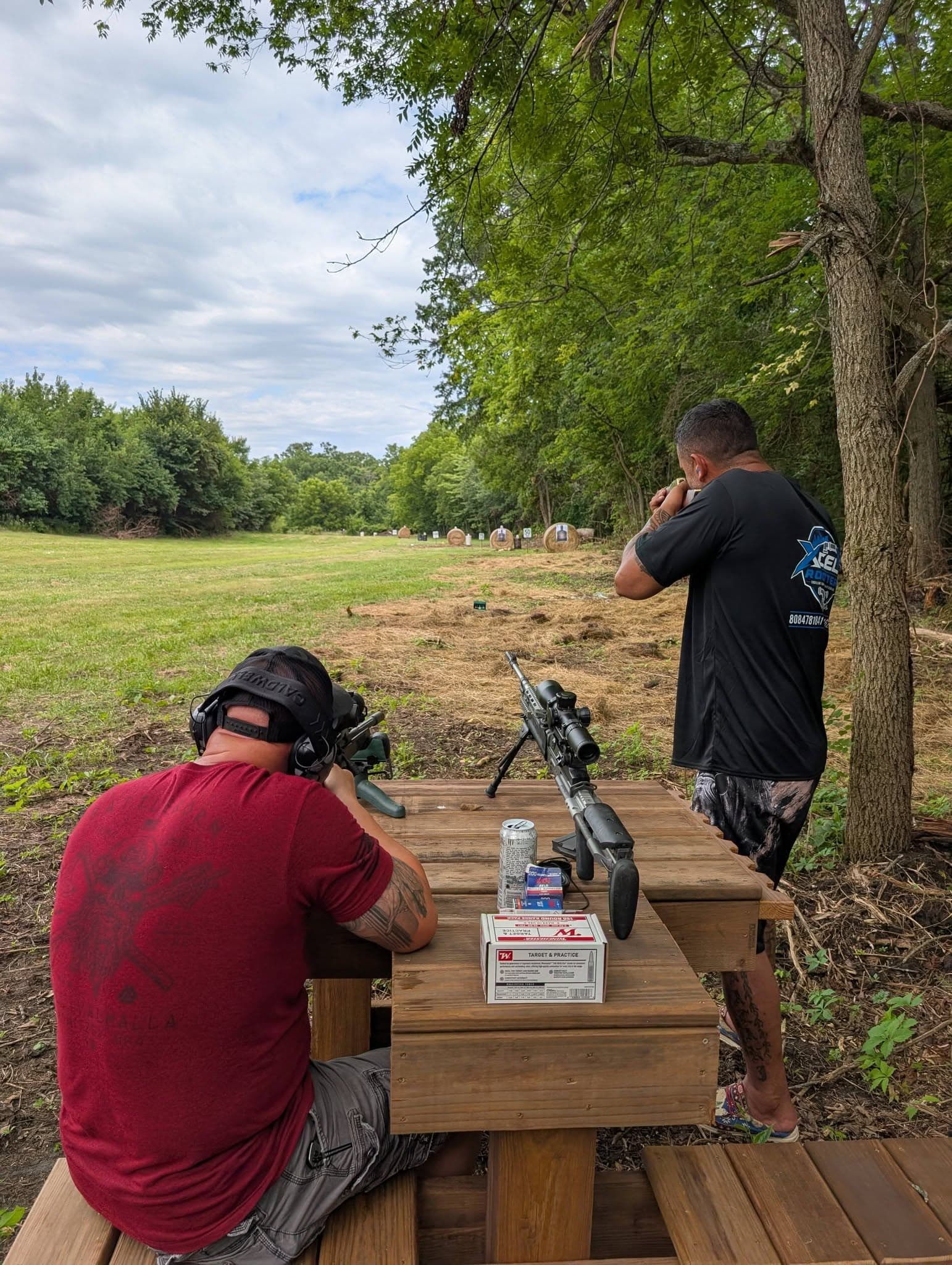 Two members at the shooting bench, one on the rifle and one glassing downrange